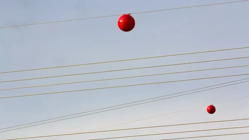 Kleurrijke bollen aan elektriciteitskabels.